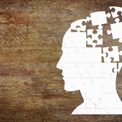 A man's head with puzzle pieces on a wooden background.