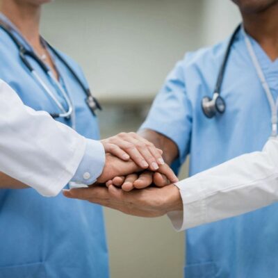 A group of doctors shake hands in a hospital.