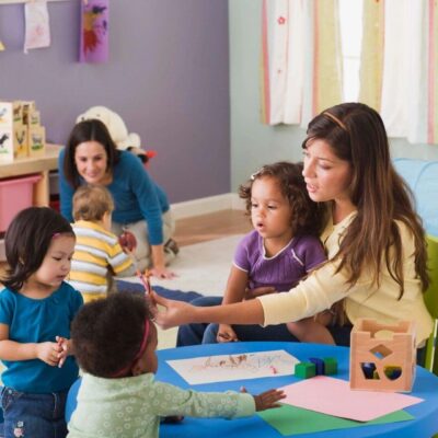 A group of children sitting at a table in a playroom.