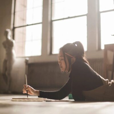 A woman laying on the floor with a pencil in her hand.