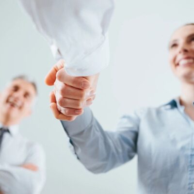 A man and woman shaking hands in an office.
