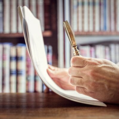 A man holding a pen in front of a bookcase.