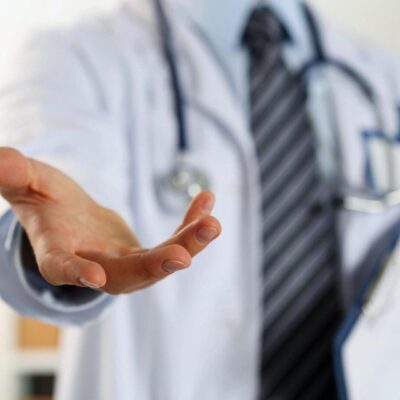 A doctor is holding out his hand to someone.