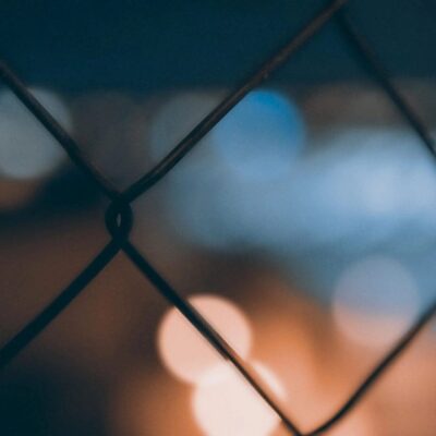 A blurry image of the fence with lights in the background.