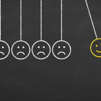 A group of smiling faces hanging from a blackboard.