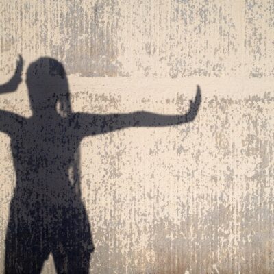 A silhouette of a woman standing in front of a wall.