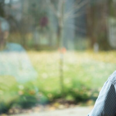 An elderly man in a wheelchair looking out of a window.