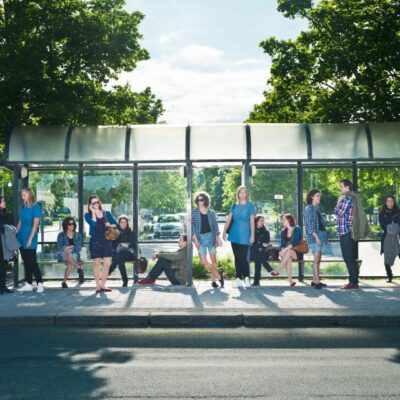 A group of people standing in front of a bus stop.
