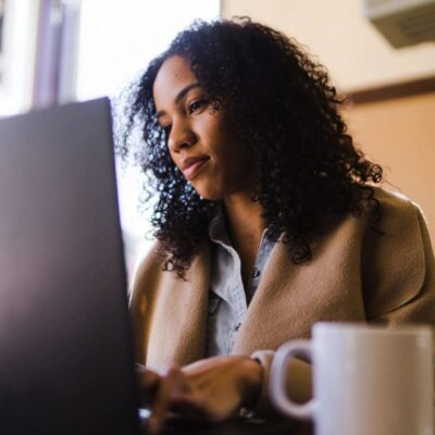 Woman working on laptop at cafe.