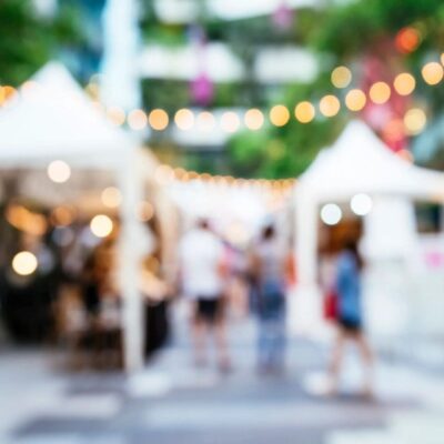 A blurry image of people walking in an outdoor market.