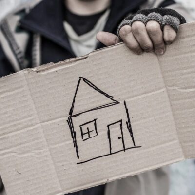 A man holding up a cardboard box with a house drawn on it.