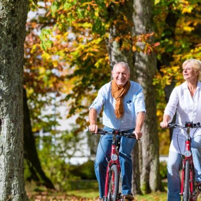 Senior couple riding bicycles in autumn park stock photo.