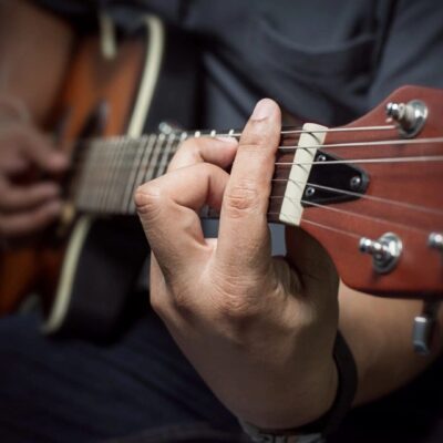 Close-up of hand playing chords on an acoustic guitar.