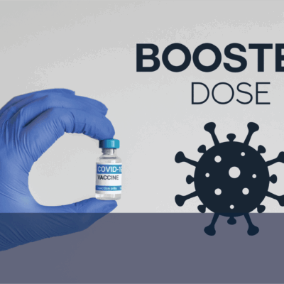 A hand holding a bottle of booster dose with the words coronavirus.