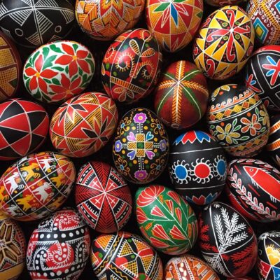 Many colorful painted easter eggs are arranged in a basket.